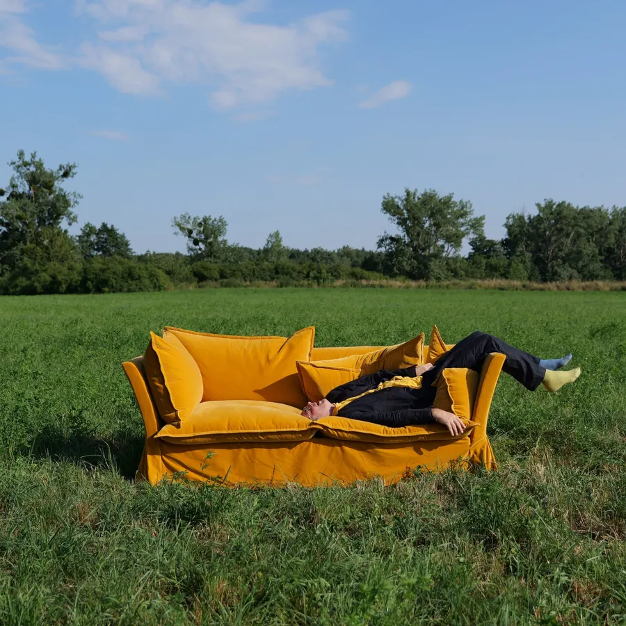 A Schplendid sofa in a field, with someone stretched out on it